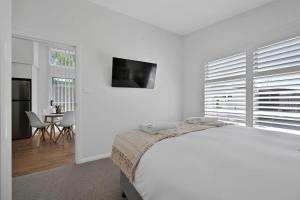 a white bedroom with a large bed and a table at The Elm Apartments - The Orange Room in Orange