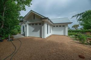 une maison blanche avec deux portes de garage sur une allée dans l'établissement Hamptons Cottage - Refined Living, Light-Filled, à Dubbo