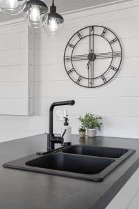 a kitchen sink with a clock on the wall at The Hidden Loft I 5-min Walk 2 Beach I DT I 55 TV in Sylvan Lake