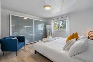 1 dormitorio con 1 cama grande y 1 silla azul en The Hidden Loft I 5-min Walk 2 Beach I DT I 55 TV, en Sylvan Lake
