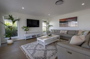a living room with a couch and a tv at The Hideaway - Close to Zoo & Golf Club in Dubbo
