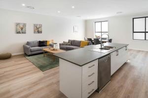 a living room with a kitchen and a living room with a couch at Crooked Lane Apartment - CBD, Stylish & Central in Wagga Wagga