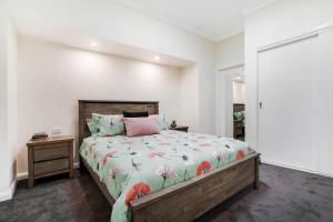 a bedroom with a large bed and a night stand at Crooked Lane Apartment - CBD, Stylish & Central in Wagga Wagga