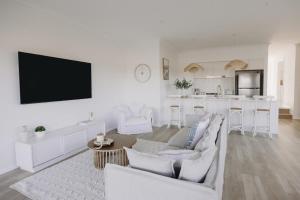 a living room with white furniture and a kitchen at Macquarie - Sleek & Stylish, Countryside Views in Dubbo