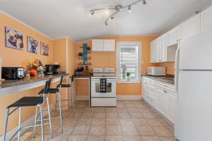 a kitchen with white appliances and orange walls at Dino Cave l Walk to Downtown l Fire Pit & BBQ I TV in Drumheller