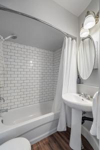 a white bathroom with a tub and a sink and a bath tub at The Icon I Sleep 4 I Heritage House I 55 Roku TV in Cranbrook