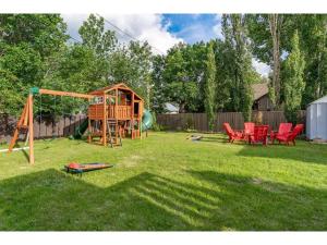 a yard with a playground and red chairs at The Riverside I Patio & BBQ I Fire pit I Sleeps 17 in Drumheller