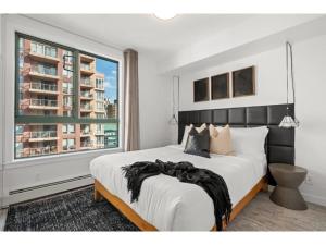 a bedroom with a large bed and a large window at The Loki I Patio & BBQ I Sleeps 5 I Downtown I TV in Calgary