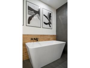 a white bath tub in a bathroom with two pictures on the wall at The Aura I Lake View I Hot Tub I Sleeps 27 Guests in Invermere