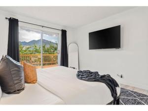een slaapkamer met een bed, een televisie en een raam bij The Aura I Lake View I Hot Tub I Sleeps 27 Guests in Invermere