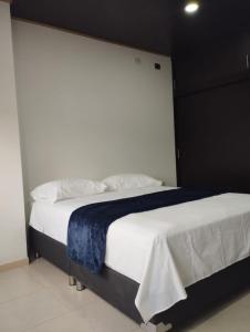 1 dormitorio con 1 cama grande con sábanas y almohadas blancas en NIRVANA APARTAESTUDIOS, en Arauca