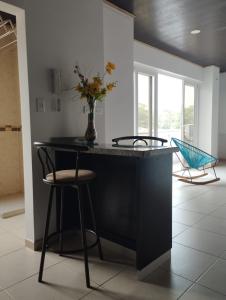 a kitchen with a counter with two chairs and a vase with flowers at NIRVANA APARTAESTUDIOS in Arauca