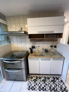 a kitchen with white cabinets and a black and white tile floor at AP Condomínio Fechado in São José dos Pinhais