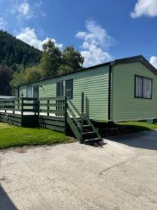 einem grünen Wohnwagen mit einem Zaun und einem Haus in der Unterkunft Swift Bordeaux Sea View 15 in Dunoon