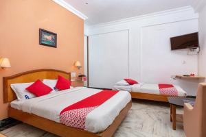 1 dormitorio con 2 camas y almohadas rojas y blancas en Collection O 5377 Hotel Raaj Bhaavan, en Chennai
