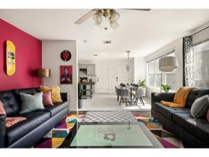 uma sala de estar com um sofá preto e uma parede rosa em Round Rocker l Backyard & BBQ l Sleeps 14 l em Round Rock