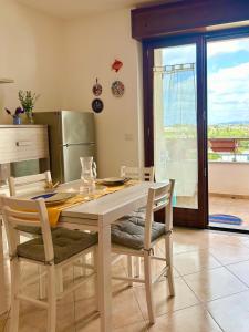 a kitchen with a wooden table with chairs and a table and a window at Nura's - Casa Nina in Alghero