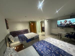 a bedroom with two beds and a flat screen tv at North Avenue, Guest House, Heathrow Airport-Free Parking in Hayes