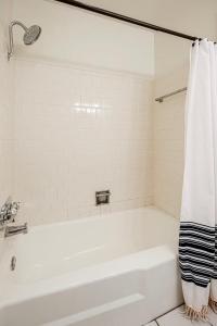 een wit bad met een douchegordijn in de badkamer bij Rancho Del Sol l Sleeps 5 l Close to Downtown I TV in Austin