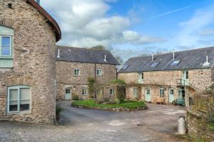 an exterior view of two large brick buildings at Cosy Cottage Huge Garden w Lake BBQs & Seating in Slapton