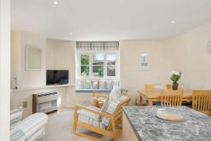 a living room with a table and chairs and a television at Cosy Cottage Huge Garden w Lake BBQs & Seating in Slapton