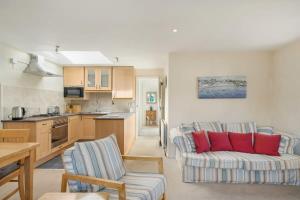 a living room with a couch and a kitchen at Cosy Cottage Huge Garden w Lake BBQs & Seating in Slapton