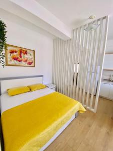 a bedroom with a bed with a yellow blanket at HC Hotel & Suites in Vlorë