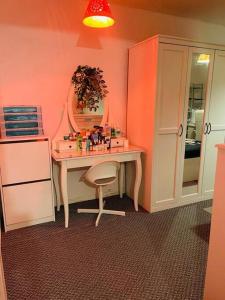 Habitación rosa con escritorio, espejo y silla. en Luxury Top Quality natural Bedroom Near the Train Station, en Barking
