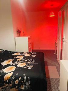 1 dormitorio con cama y pared roja en Luxury Top Quality natural Bedroom Near the Train Station, en Barking