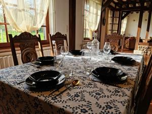 einen Tisch mit einem Tischtuch mit Tellern und Weingläsern in der Unterkunft Maison Évasion Normande in Sainte-Opportune-la-Mare