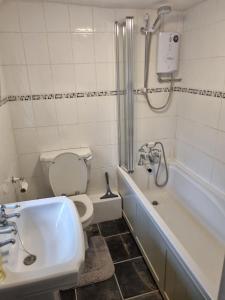 a bathroom with a tub and a toilet and a sink at Idyllic Cottage in Dorset Garden & Parking in Gillingham