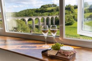 two glasses of wine sitting on a table next to a window at Charming Cottage with Stunning Views in Calstock
