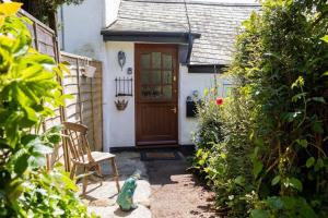una pequeña casa con una puerta de madera y una silla en Charming Cottage with Stunning Views, en Calstock