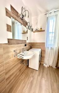 ein Badezimmer mit einem Waschbecken, einer Waschmaschine und einem Trockner in der Unterkunft Casa Emma in Porto Ceresio