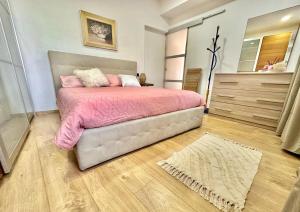 1 dormitorio con 1 cama con sábanas rosas y espejo en Casa Emma, en Porto Ceresio