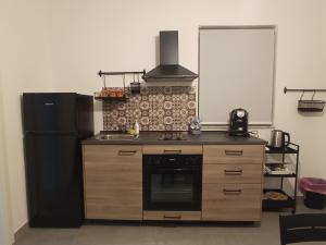 een keuken met een zwarte koelkast en een fornuis bij GrotteBianche - Sicilian Apartment in Catania