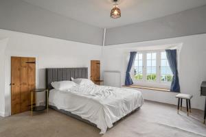 a white bedroom with a bed and a window at Secluded Cottage w Expansive Sea Views & Garden in Culbone