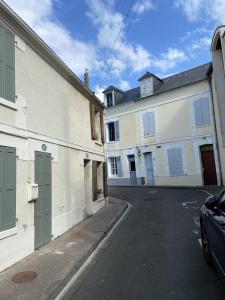 an empty street with two white buildings and a car at Maison de pêcheur Valentine à Trouville in Trouville-sur-Mer