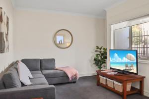 a living room with a couch and a table with a tv at Little Malop Escape I Central Geelong in Geelong