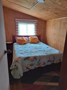 Bett in einem kleinen Zimmer mit Fenster in der Unterkunft Cabaña Alba in Puerto Montt