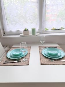 a white table with two plates and wine glasses at Angela's house in Sofia