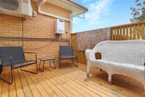 a patio with a white couch and chairs on a wooden deck at 14 Scenic Studio in Geelong