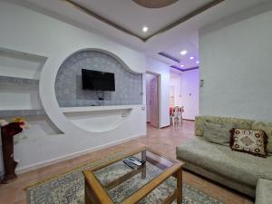 een woonkamer met een bank en een tv aan de muur bij Résidence Karim in Djerba