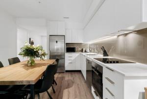 uma cozinha com armários brancos e uma mesa de madeira em Te Awa at La Residence du Parc em Queenstown
