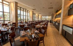 a dining room with tables and chairs and windows at Cullinan Hplus Premium Flat Vip in Brasilia