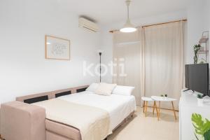 ein weißes Schlafzimmer mit einem Bett und einem TV in der Unterkunft Koti Rentals - Nenúfar in Fuengirola