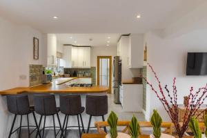 een keuken met witte kasten en barkrukken bij Spacious 4Bed Home: Elegant Garden & Parking in Windsor