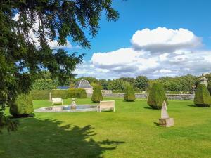 un jardín con un estanque y una mujer sentada en un banco en North Wing - Pitmedden Gardens, en Ellon