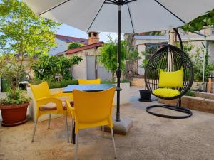 einen Tisch mit gelben Stühlen und einem Regenschirm in der Unterkunft Kuća za odmor EMA in Šibenik