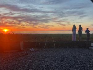 3 personnes debout sur un mur en regardant le coucher du soleil dans l'établissement Rataview, à Barrytown